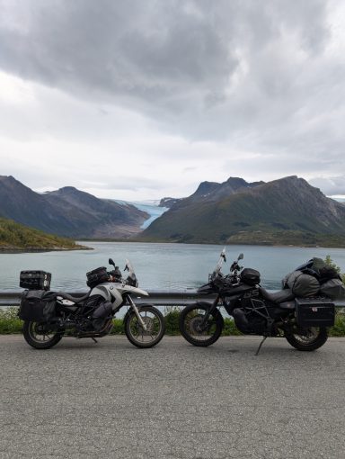 2 Motorräder vor einem See, im Hintergrund sieht man eine Gletscherzunge zwischen den Bergen