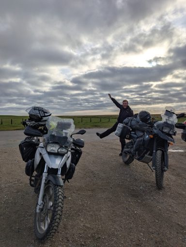 Nico steht hinter seinem Motorrad und streckt den Arm in die Luft